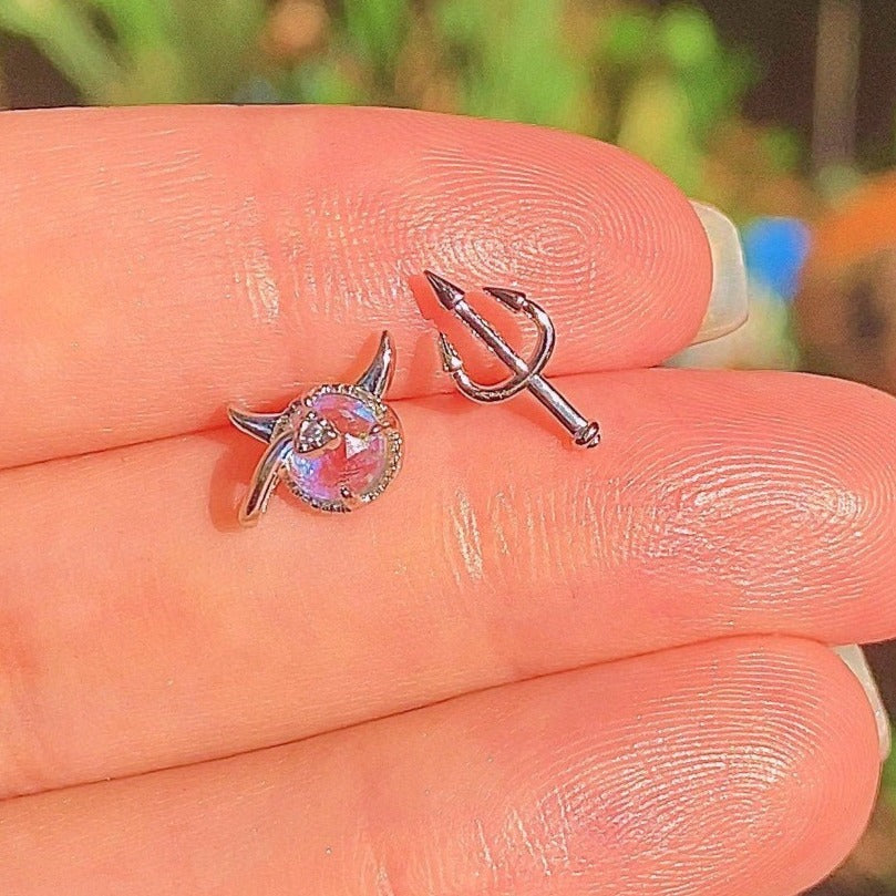 Asymmetrical devil earrings studs in hand
