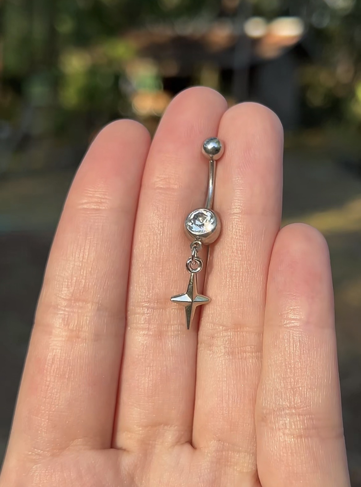 Silver belly button ring with a tiny star sparkle pendant