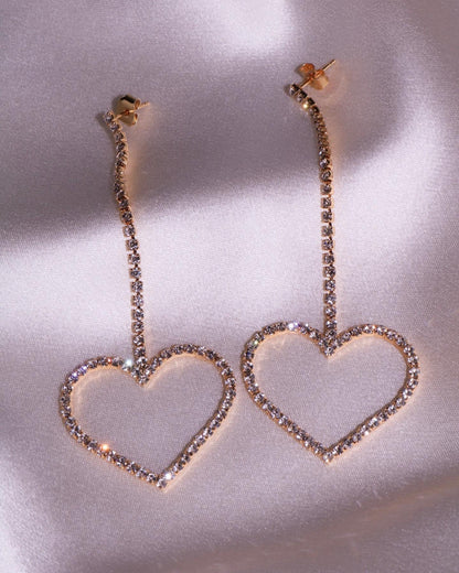 gold heart drop earrings with cubic zirconia and stud backing on pink silky backdrop 