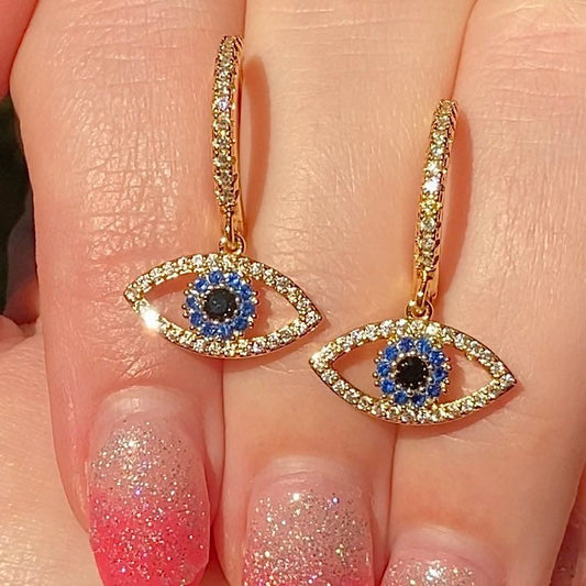 evil eye drop huggie earrings with blue eye in centre held in fingers 