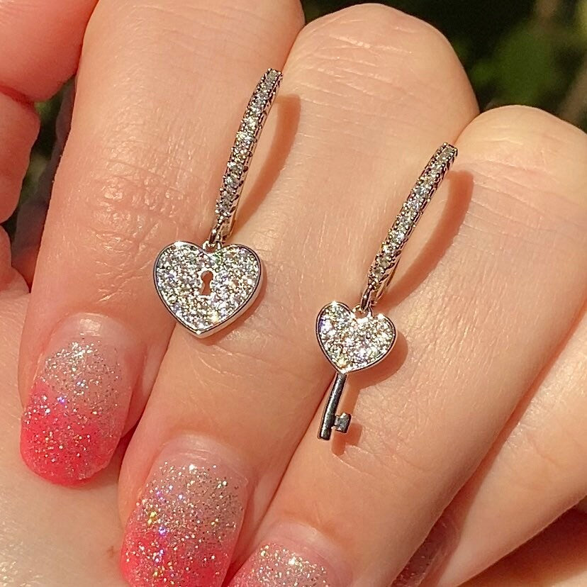 two asymmetrical heart and heart hey in silver sitting in fingers